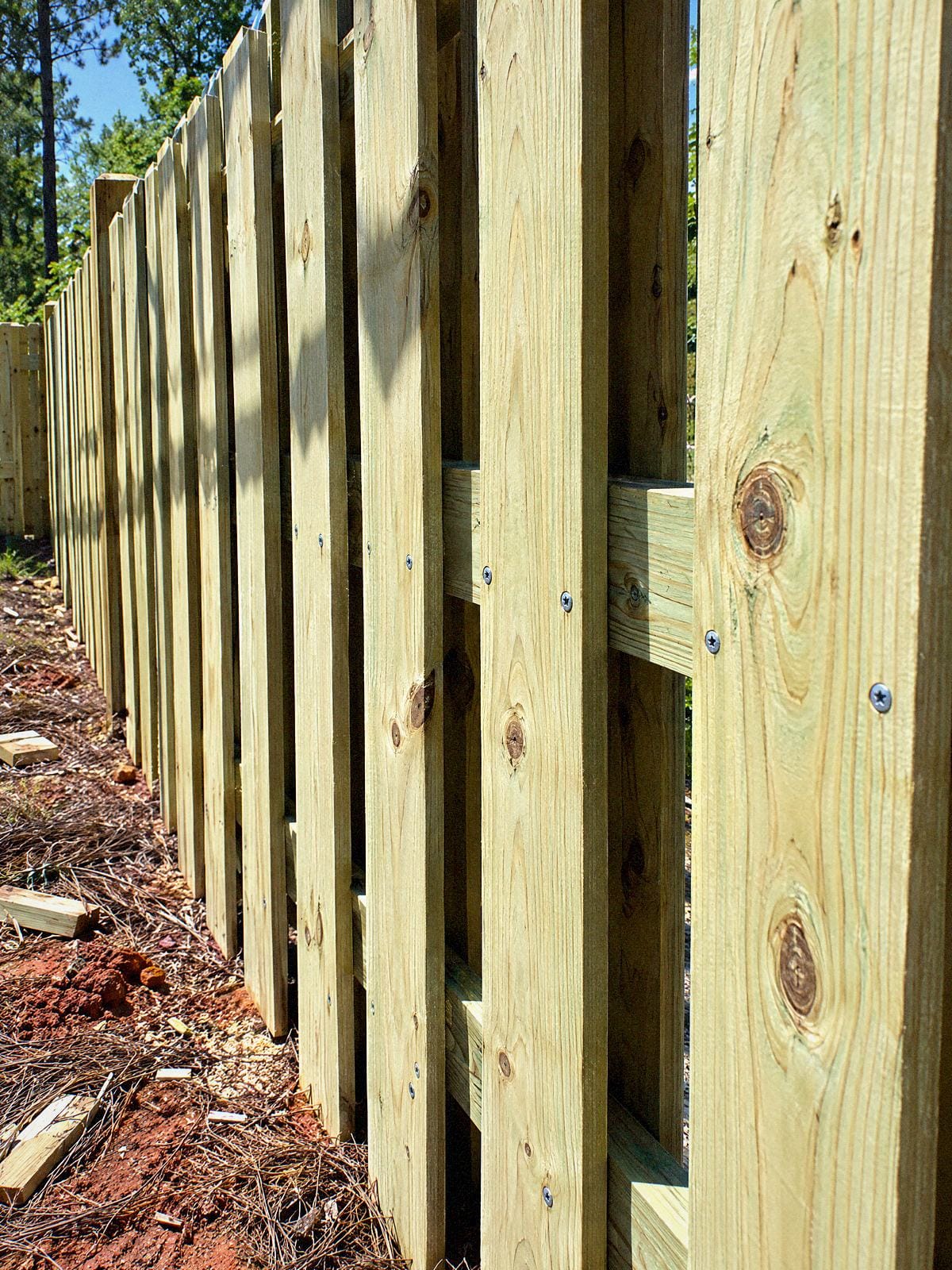 Close view along a shadowbox fence showing boards on both sides of the rail with gaps between them